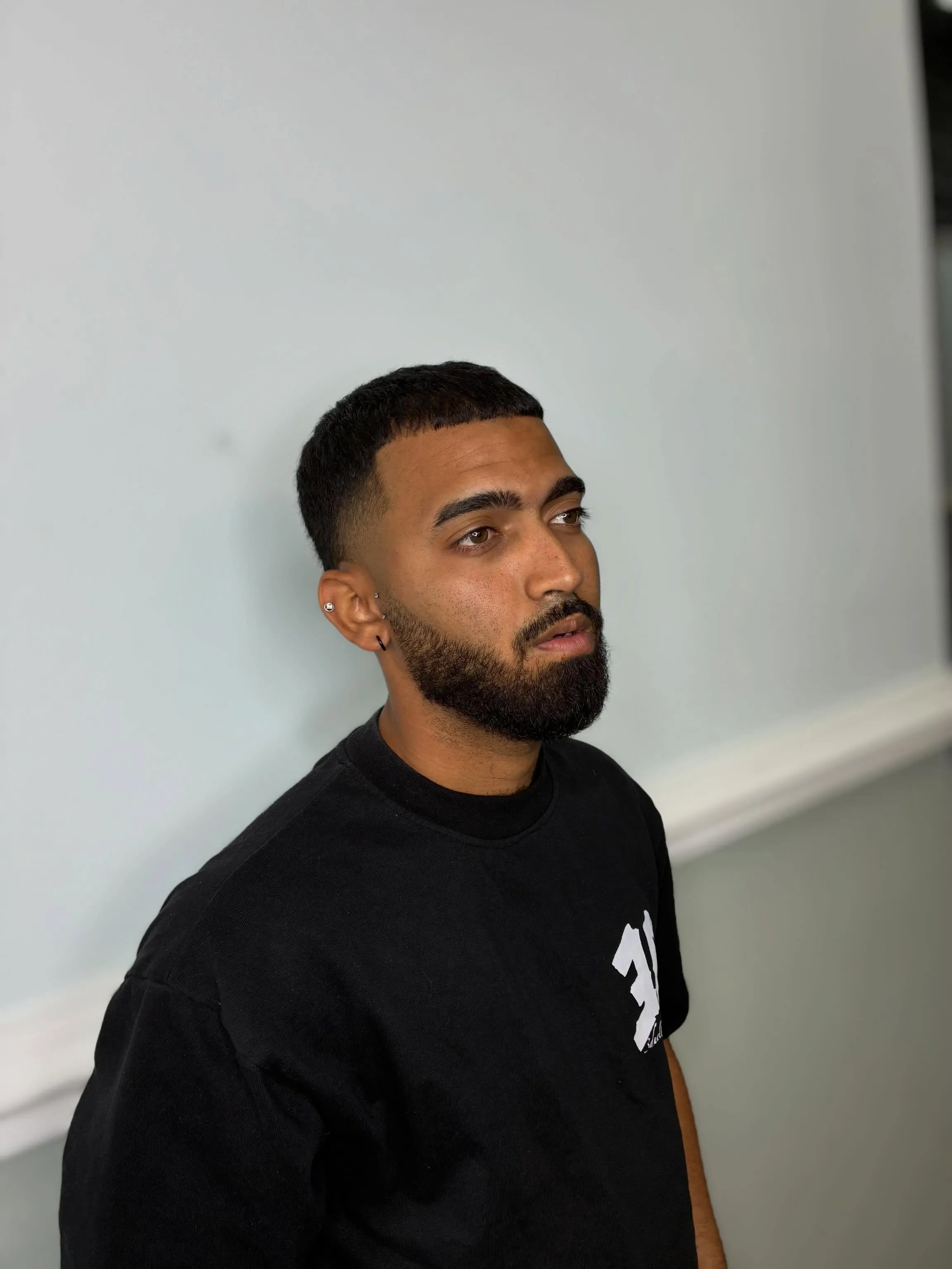 Low fade with a shaped full beard, three-quarter view
