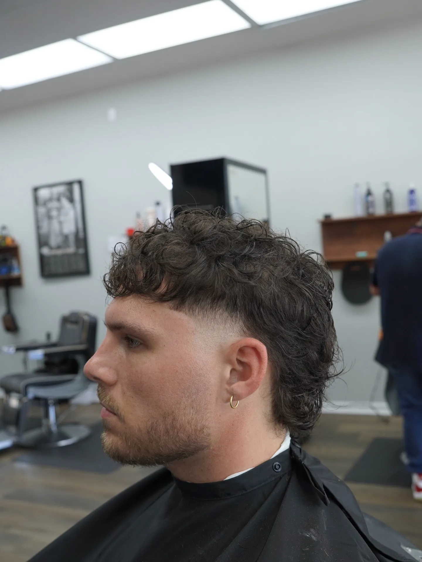 Curly mullet with a burst fade over the ear, side profile