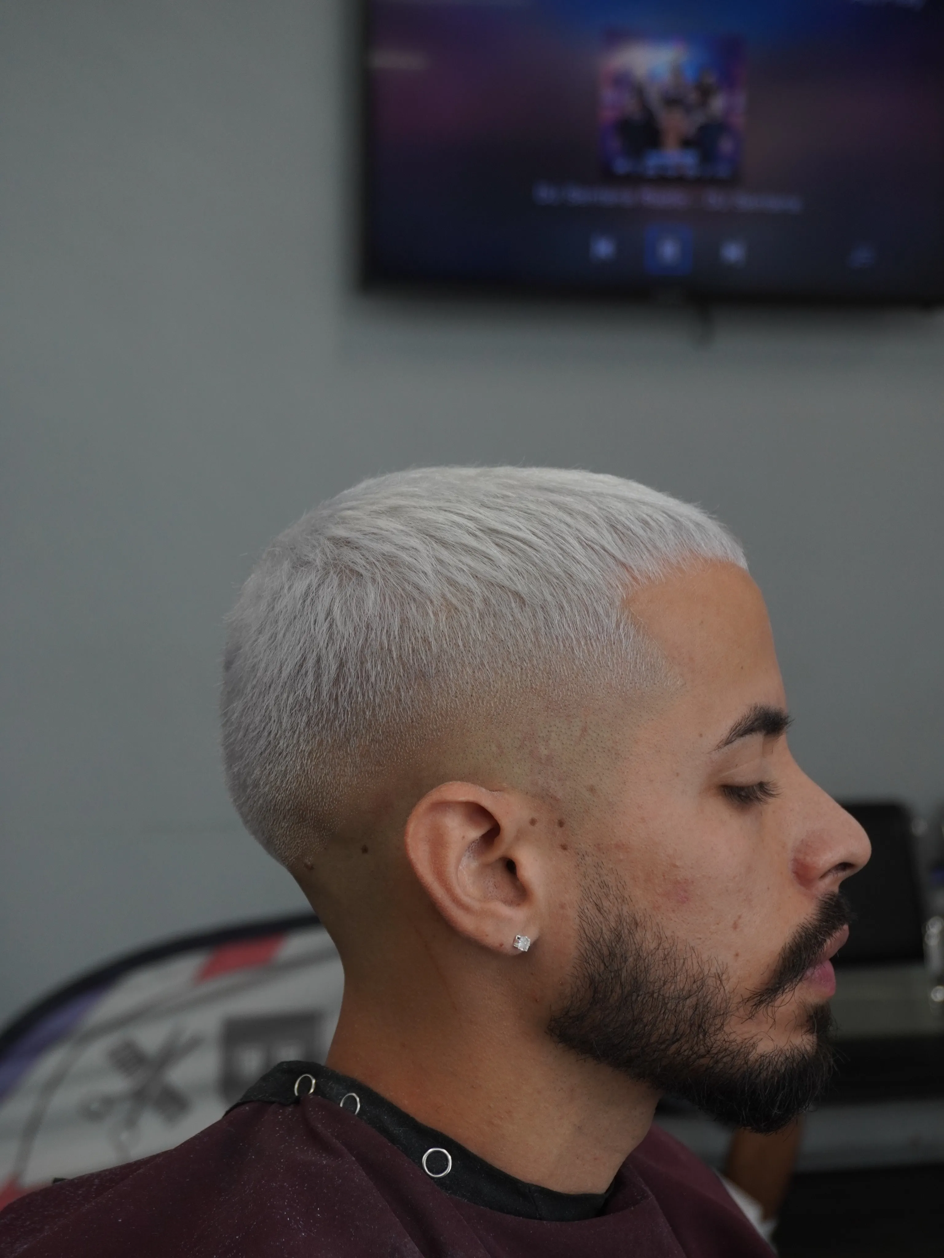 Platinum blond skin fade with a lined beard, side profile, in the chair at Mad Barbers Avalon Park